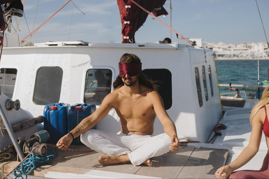 Man meditates on a boat wearing a Vivida sleep mask