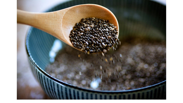 A spoonful of chia seeds being added to a bowl - Vivida Lifestyle