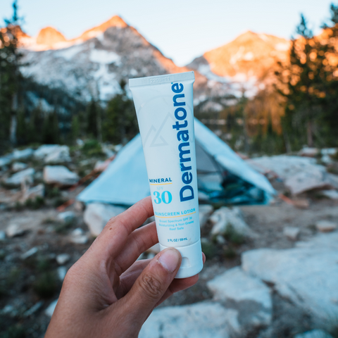 Dermatone Mineral SPF30 Sunscreen Lotion being held up in front of a tent in the Sawtooth Mountains in the fall