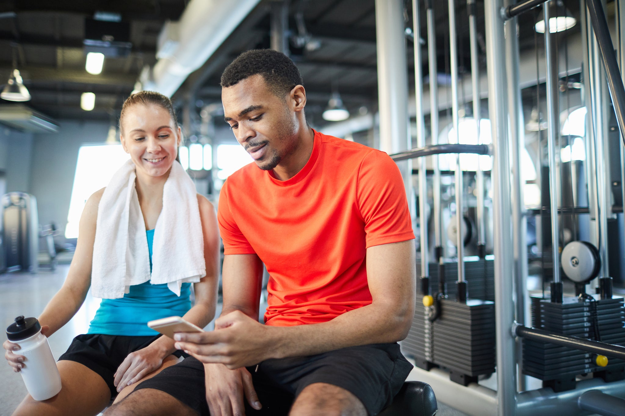 man and woman at gym checking their phone