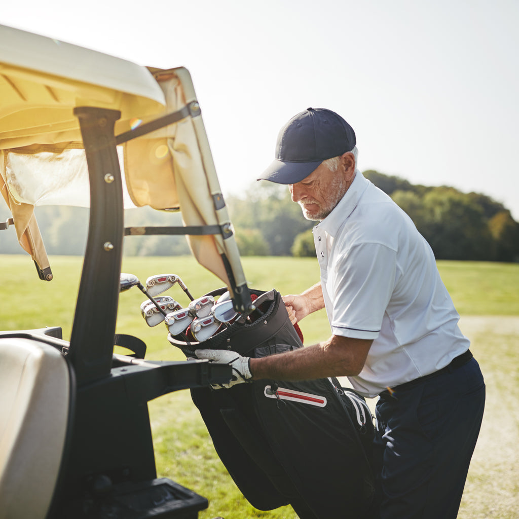 Man taking golf clubs from back of golf cart