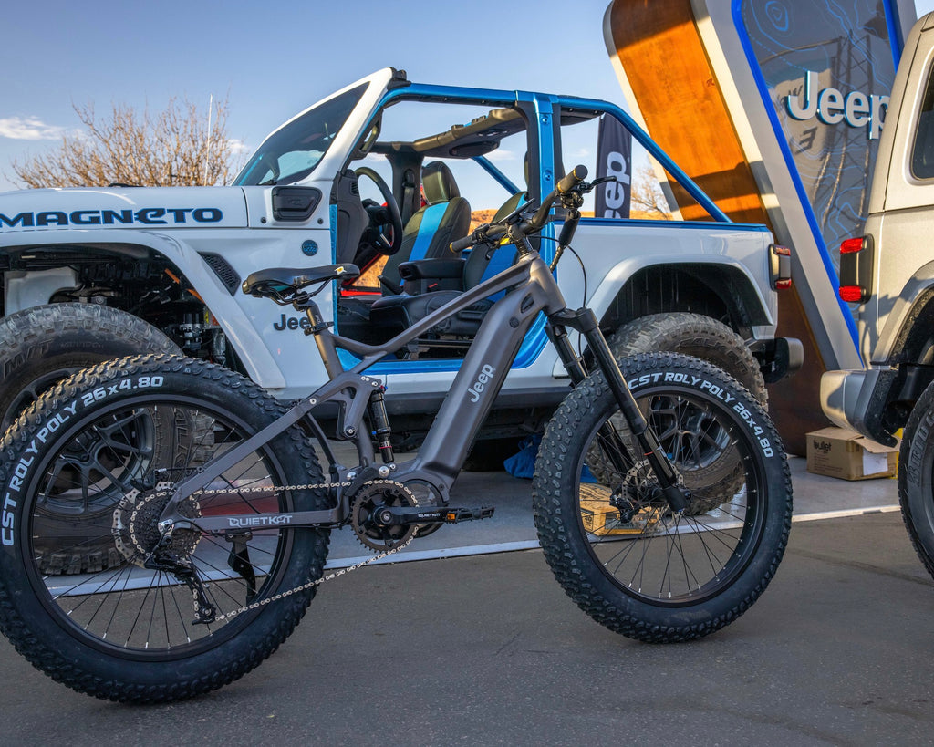 Un vélo électrique Jeep QuietKat est garé à côté d'un Jeep Wrangler blanc