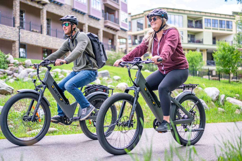 a man and a woman ride there QuietKat Villager eBike through town