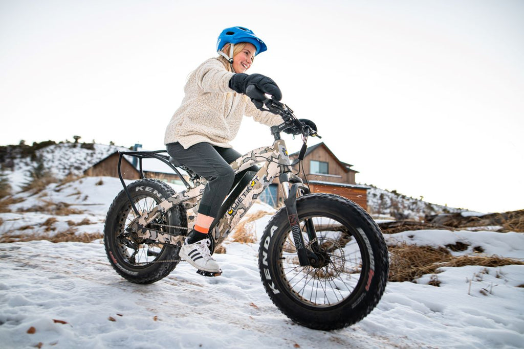 A girl rides her QuietKat Ripper eBike for kids down a snowy path