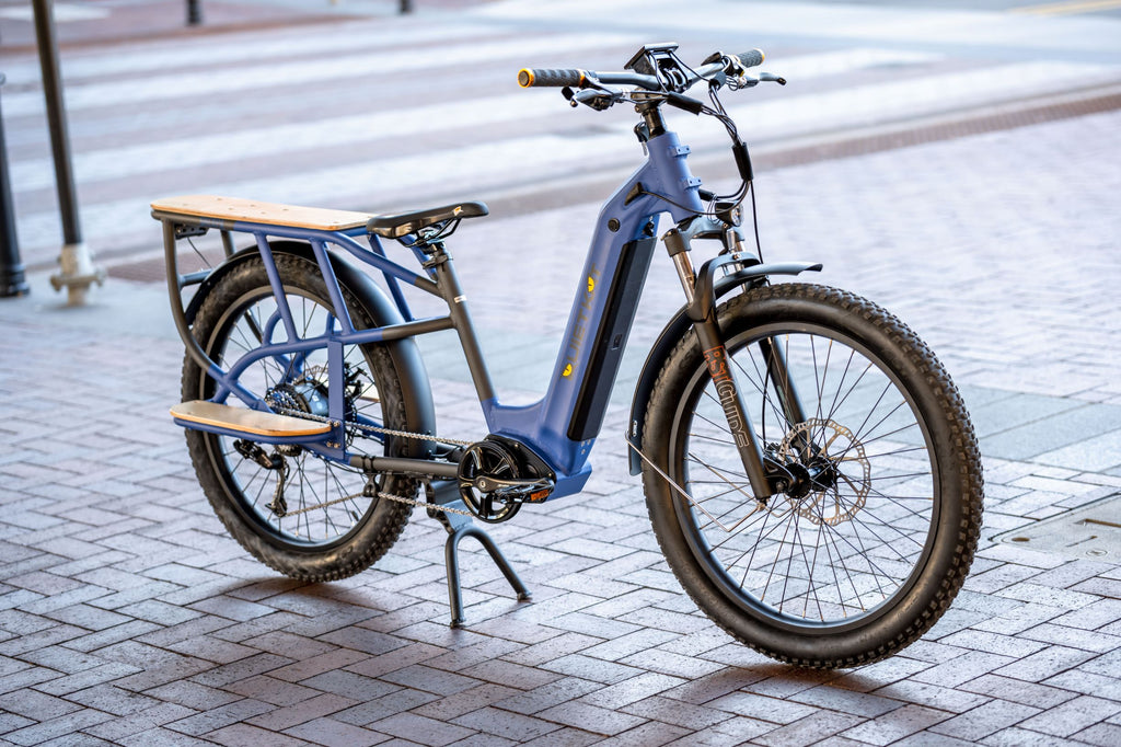 Un vélo électrique QuietKat Sherpa bleu est garé sur un trottoir du centre-ville