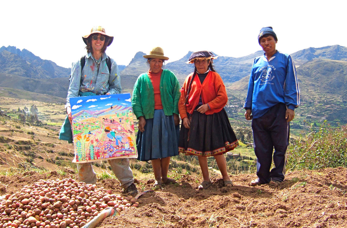 John Dyer high up in the Andes of Peru holding a painting of the potato harvest and alongside local Peruvian potato farmers.