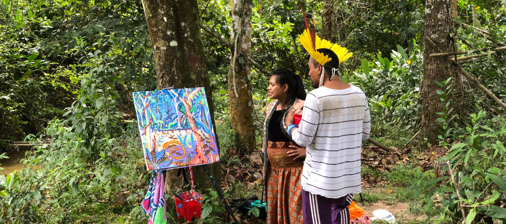 Matsa and Nixiwaka Yawanawá in the Amazon rainforest looking at a John Dyer Amazon Rainforest spiritual painting