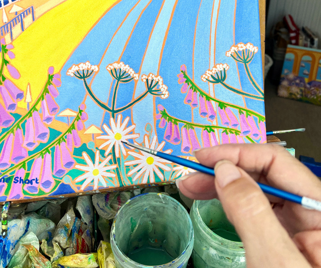 Joanne Short painting a beach painting in her art studio using oil paint.