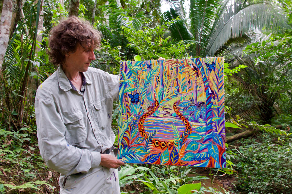 John Dyer in the Amazon rainforest holding his latest jungle painting