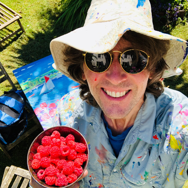 Cornish artist John Dyer pictured in his sub-tropical garden in Cornwall with fresh raspberries and a painting