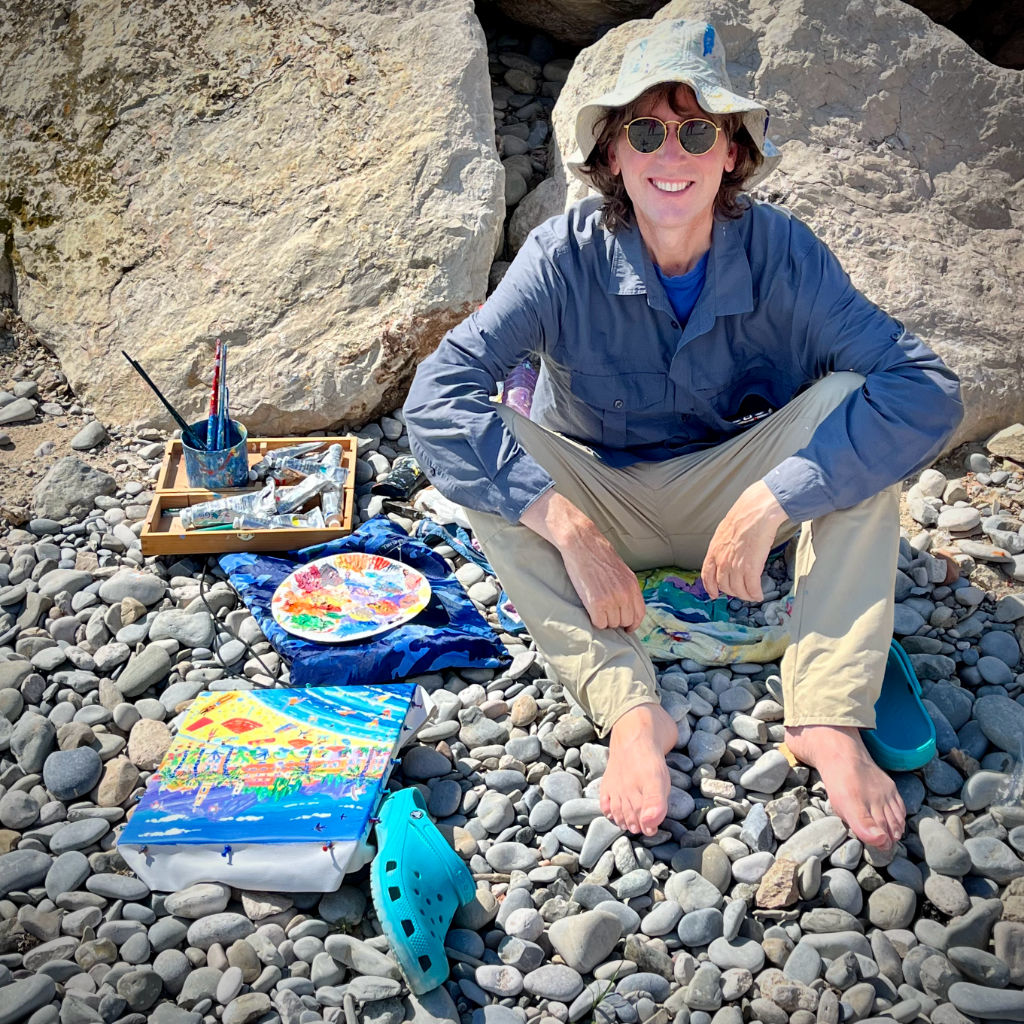 Artist John Dyer on the beach at work on a painting of Menton in France.