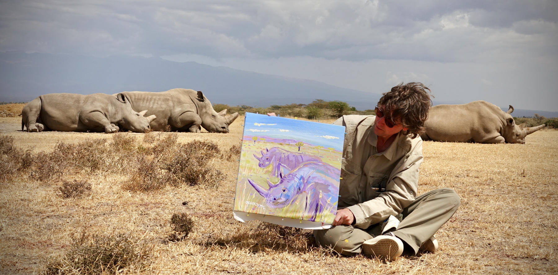 John Dyer pictured with one Southern White Rhino and the last two Northern White Rhino in Kenya at Ol Pejeta with he Northern White Rhino painting