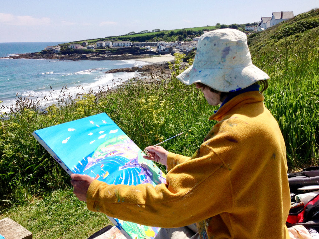 Artist John Dyer at work on a beach painting of Portscatho in Cornwall