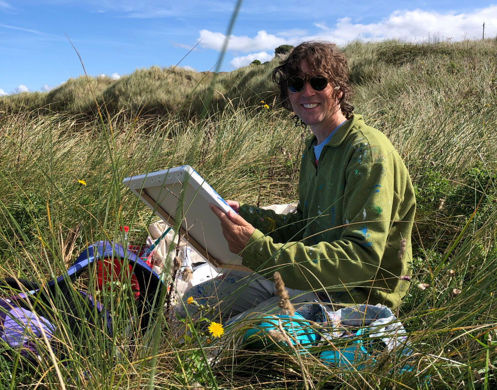 Artist John Dyer pictured painting in the dunes at Gwithian on the north Cornish coast