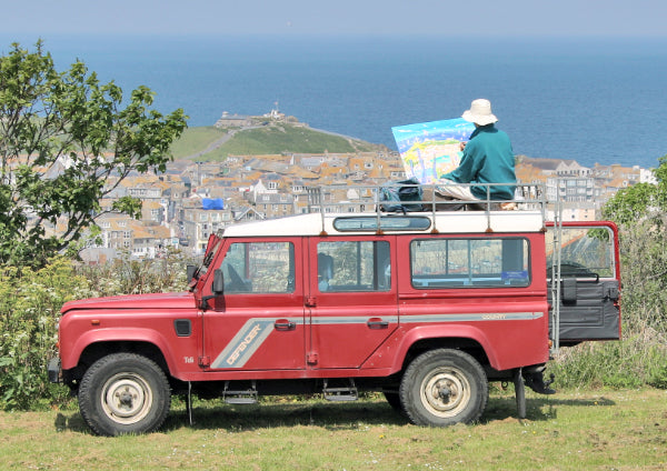 Photograph of artist John Dyer sitting on his Landrover painting St Ives