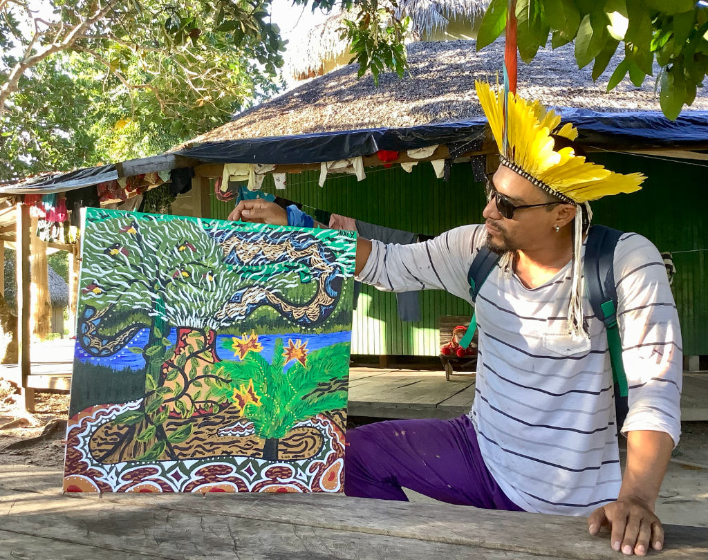 Amazon Indian artist Nixiwaka Yawanawá pictured with one of his paintings in his tribal village of Mutum in the Amazon Rainforest in June 2019