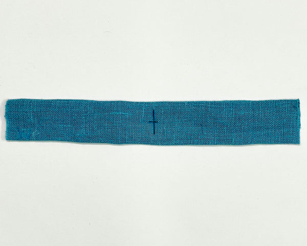 The horizontal and vertical centerline marked in black on a blue dress strap.