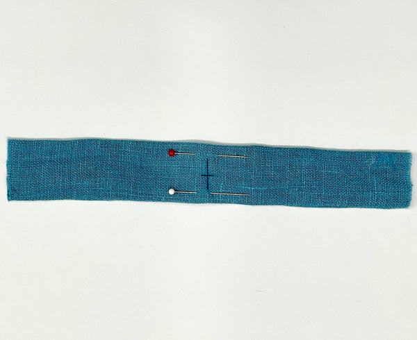 A blue dress strap with pins marking 3/8" (10mm) from the centerline on each side.
