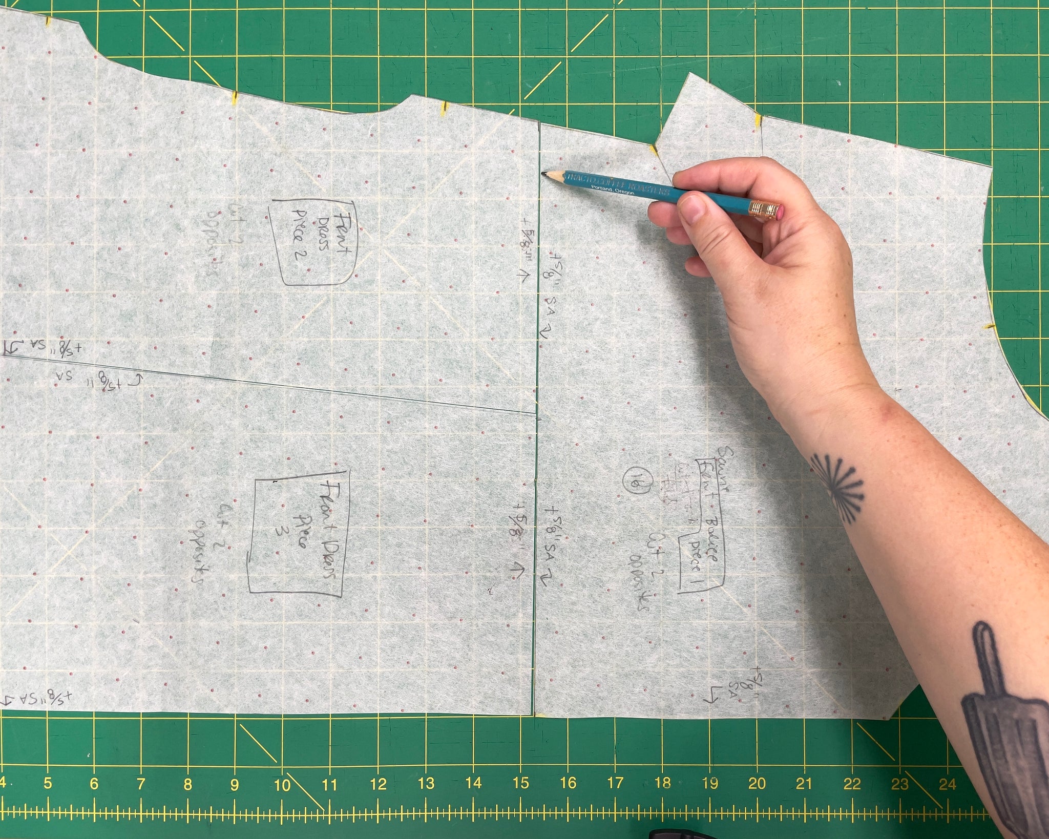 The traced front dress pattern piece from the Sauvie Sundress. A hand is using a pencil to show a line bisecting the pattern piece.