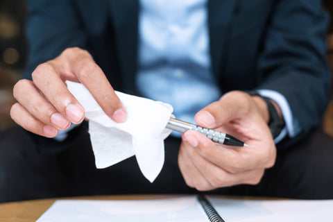 A man in a suit cleans a pen with tissue.