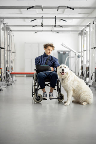 Mann mit Behinderung im Rollstuhl mit seinem Assistenzhund in einem Rehabilitationszentrum