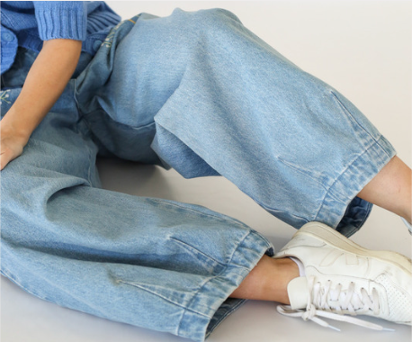 Person sitting on the ground wearing jeans in front of white background.