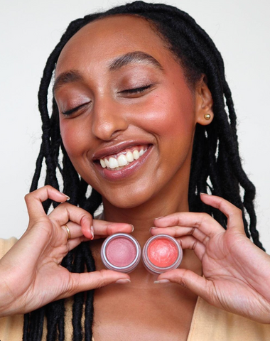 Woman with dark skin tones showing maube vs red blush comparison on each cheek