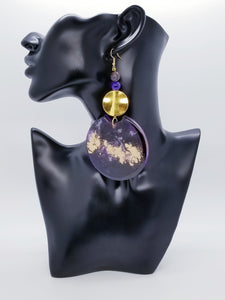 Length: 5 inches | Weight: 2.5 ounces  Distinctly You! The earrings are handmade using gold and purple hand poured resin discs, gold metal discs, 10mm purple frosted glass beads, 10mm purple swirl ceramic beads, gold head pins, and hypoallergenic hooks with back closures. 