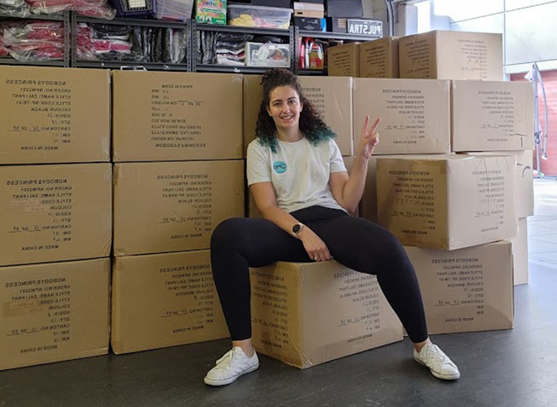 Nobody's Princess owner Maria sitting in the warehouse after moving the boxes of Zali snow pants that just arrived. 