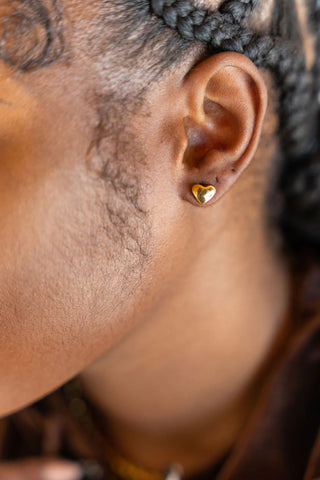 Close-up of Black female wearing gold Ella's Element Dainty Heart Studs | Stainless Steel Jewelry | E's Element