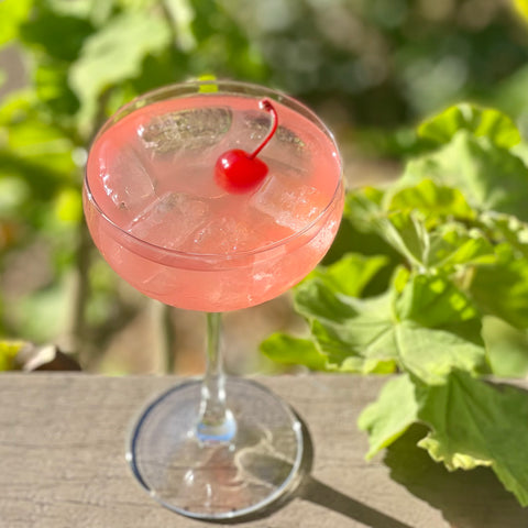 Light pink cocktail with maraschino cherry