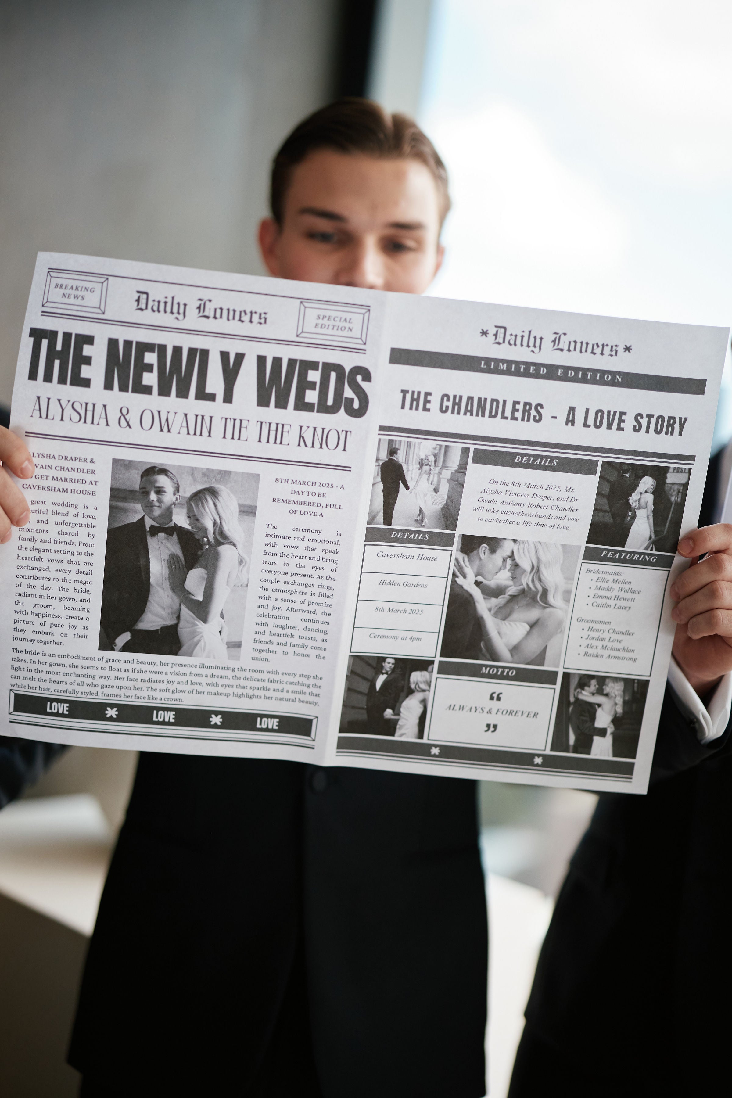 real wedding - ally and Owain - groom standing in suit and reading a newspaper that is a print of the bride and groom's wedding