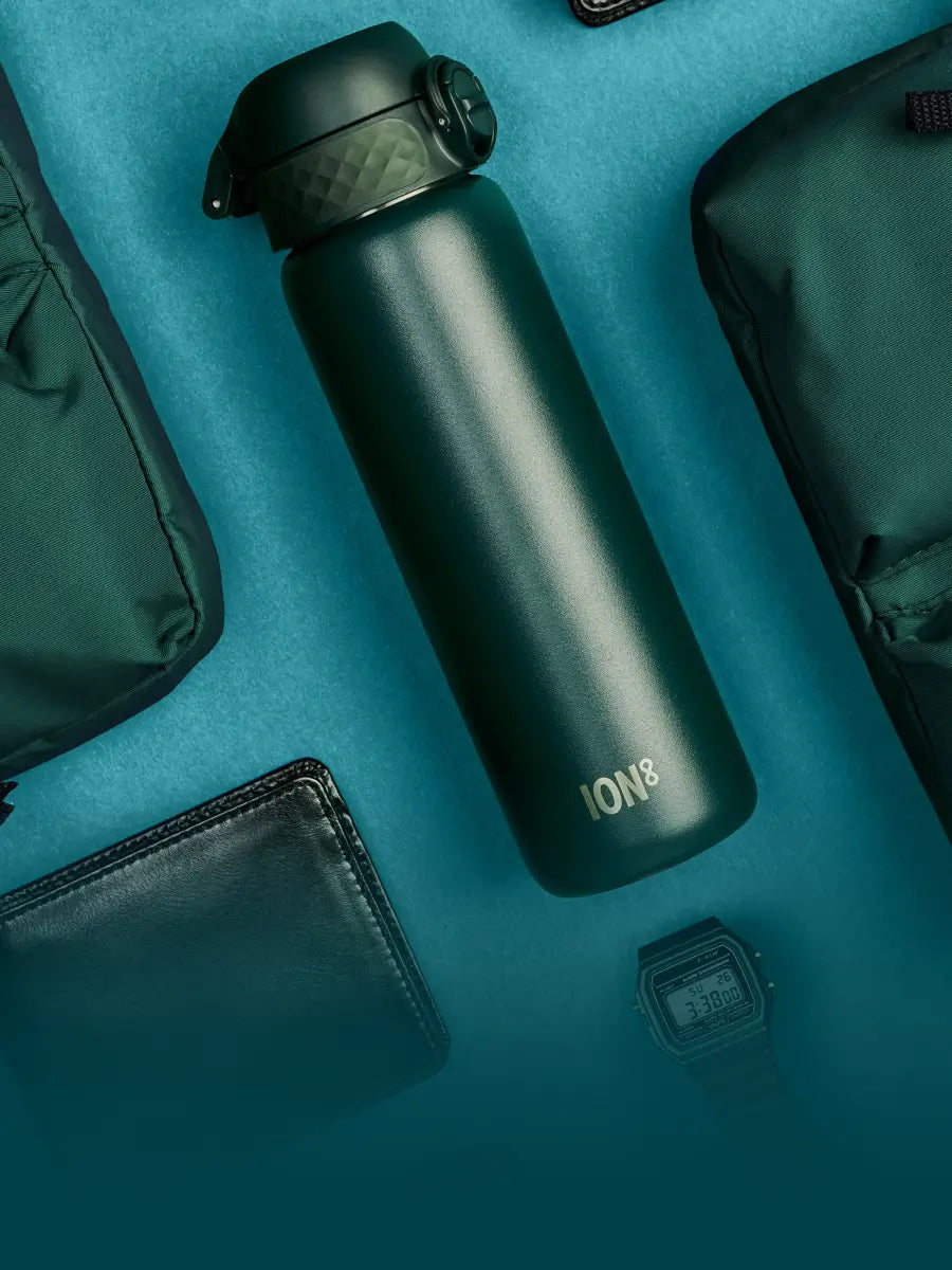 dark green stainless steel bottle amongst other dark green lifestyle accessories