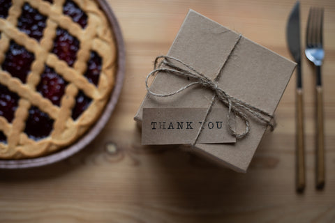 nota de agradecimiento con un regalo navideño junto a una tarta casera