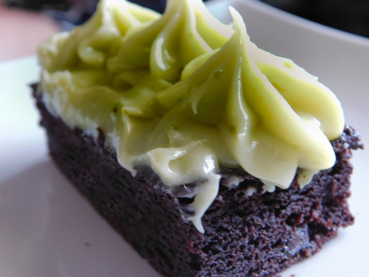 a piece of Chocolate Avocado Cake with bright green icing pipped on top