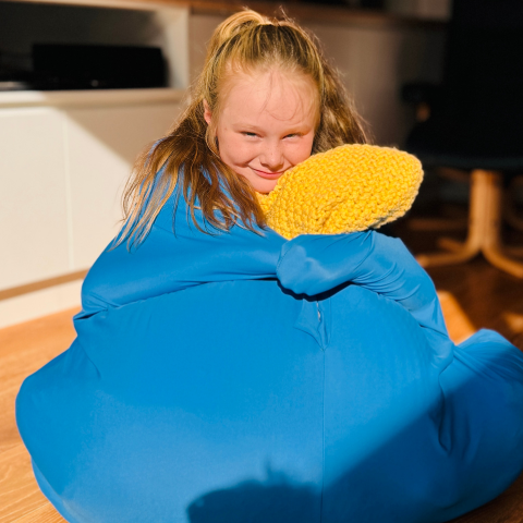 A young girl sitting on the timber floor wearing the lycra body sock