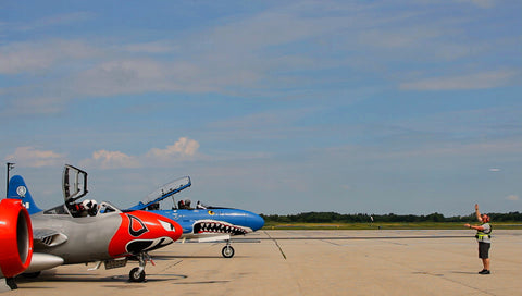 A man facing three jets on the asphalt ramp at an airport