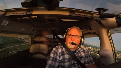 A man wearing an aviation headset flying a small plane