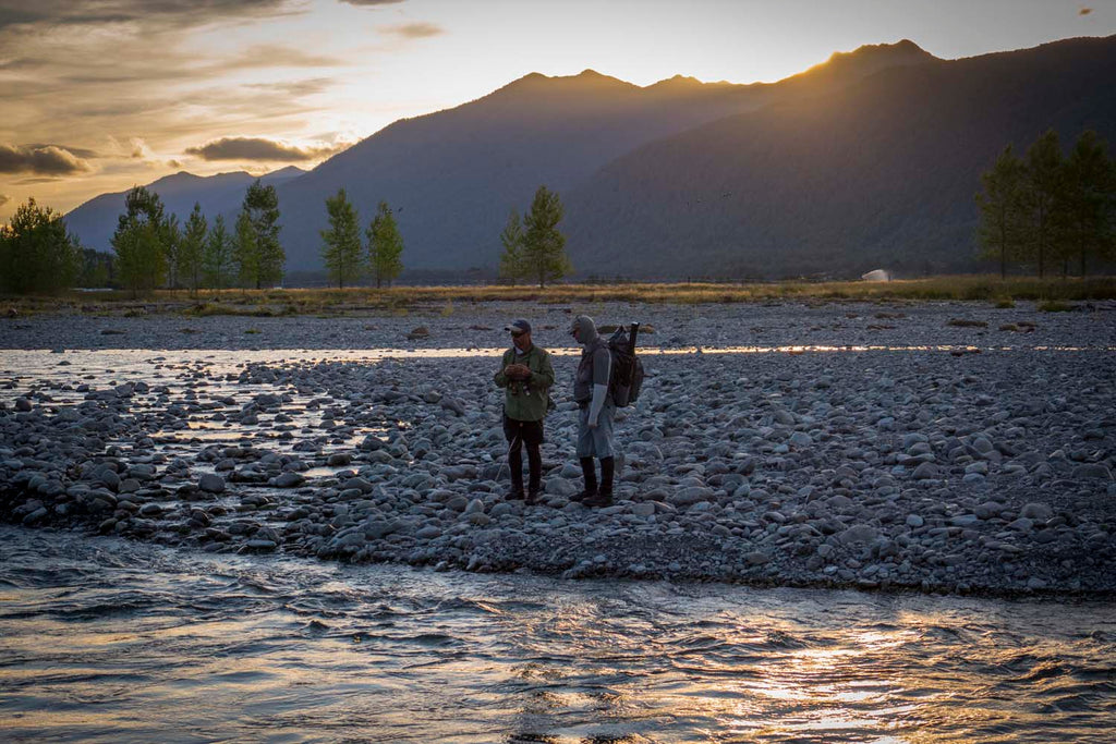 Two fly fisherman stand next to a south island river in new zealand