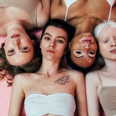 Four women of colour lying on the floor looking up