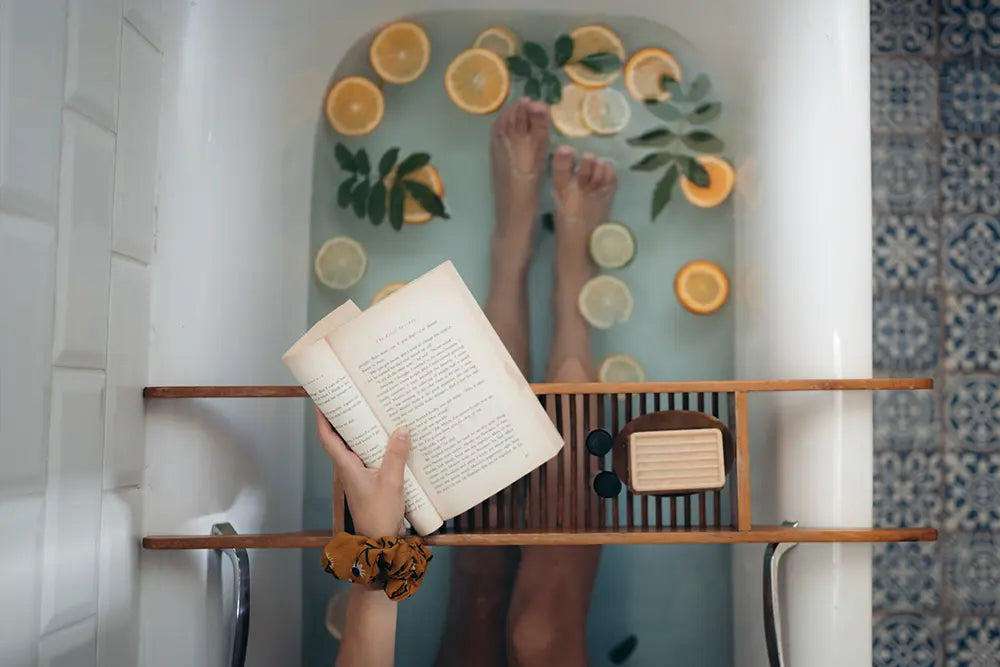 femme jambes dans une baignoire rempli de rondelles de citron qui lit un livre beauté bien etre