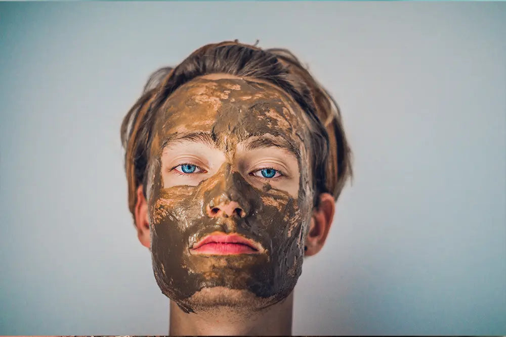 hombre de ojos azules que tiene un tratamiento con máscara de algas en la cara