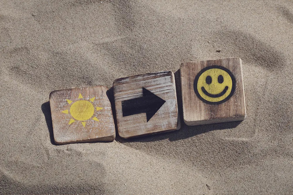 planches en bois emoji soleil fleche peint dessus sur le sable