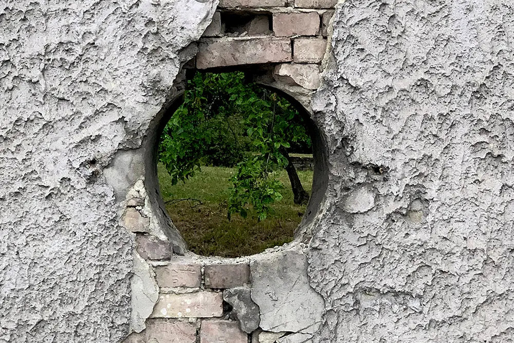 trou dans un mur en pierre qui laisse apercevoir nature jardin vert