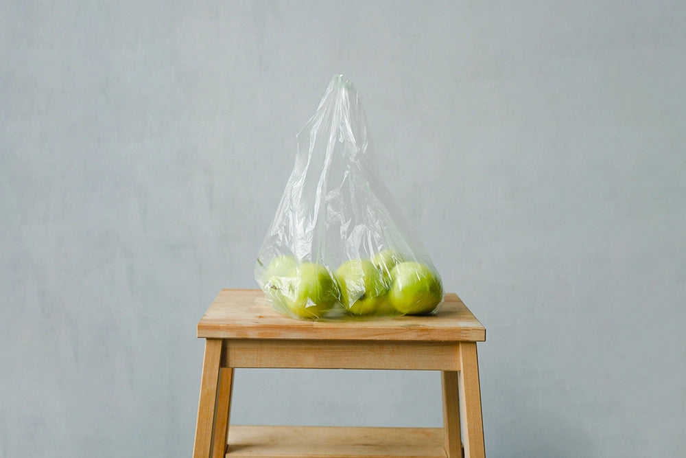 manzanas en una bolsa de plástico sobre un taburete de madera