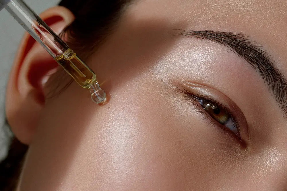 fille eurasienne met huile apaisante visage sur sa peau après soleil pour réparer sa peau du soleil et avoir une belle peau applique l'huile sur sa joue avec pipette