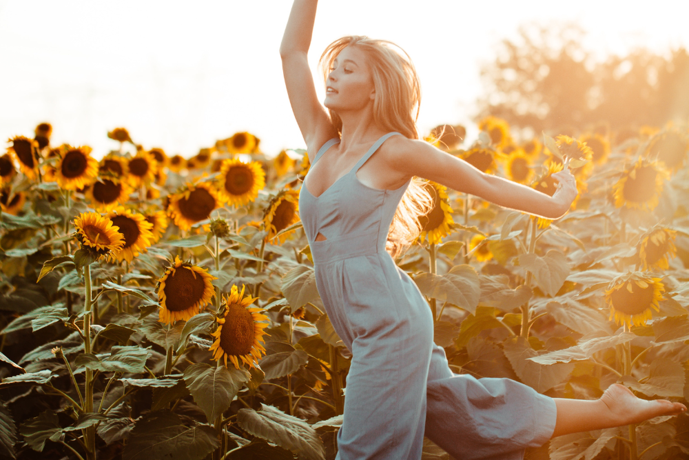 femme vitalité pleine d'énergie cheveux blonds beaux longs cours dans un champ de tournesol pleine de vie complexe vitalité