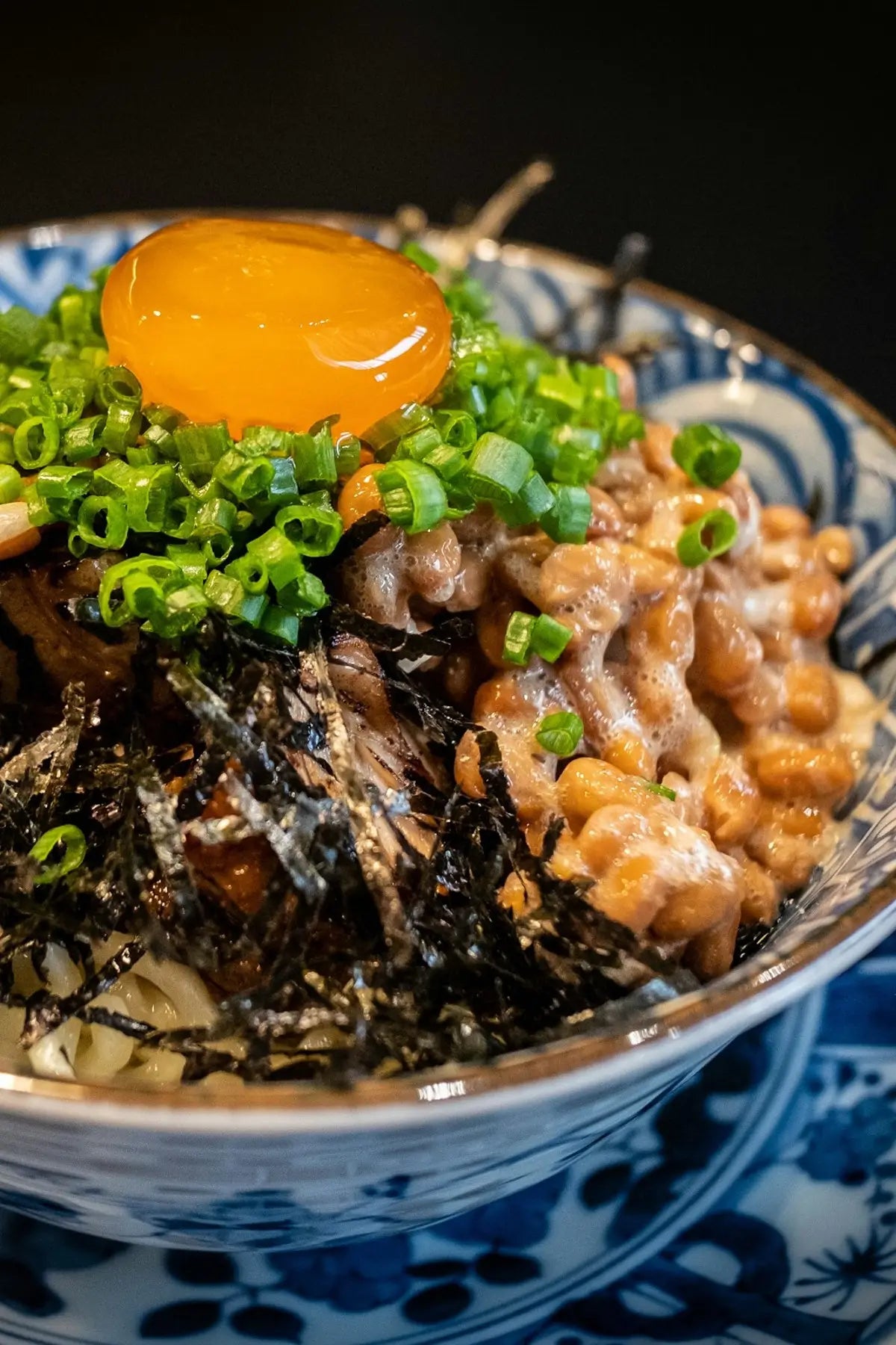 Mazesoba Natto Recipe using our freeze-dried, organic natto and organic spices, served in a Japanese blue and white bowl and topped with an egg yolk from pasture-raised hens.
