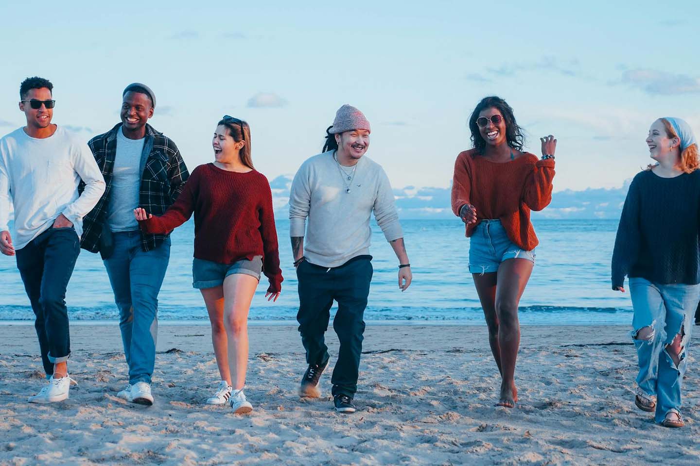 group of friends talking and smiling while walking on the beach