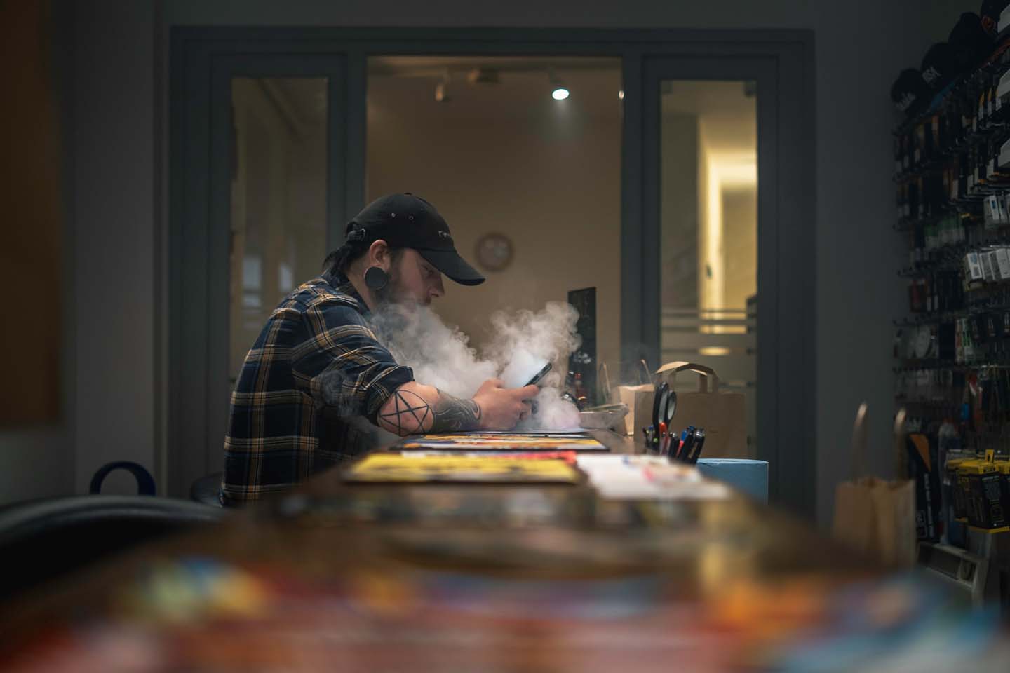 man sitting on a chair vaping while looking at this mobile phone